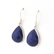 Teardrop-shaped blue lapis earrings with silver hooks on a white background