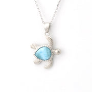 Turtle-shaped pendant with blue stone on a white background
