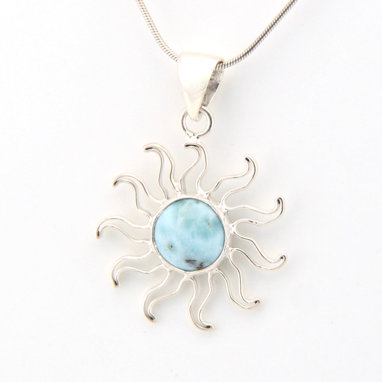 Silver sun-shaped pendant with a blue stone on a white background