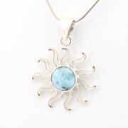 Silver sun-shaped pendant with a blue stone on a white background