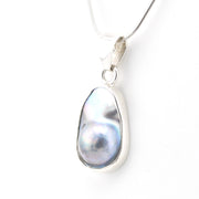 Pearl pendant on a silver chain against a white background