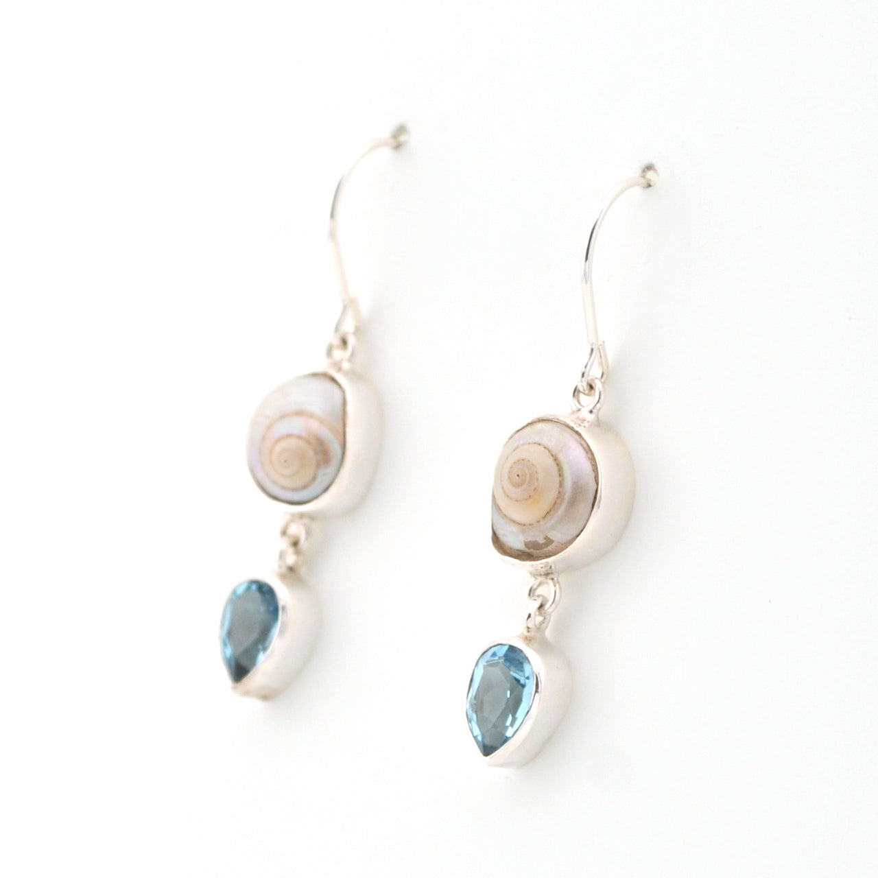 Pair of earrings with shell and blue gemstone drops on a white background