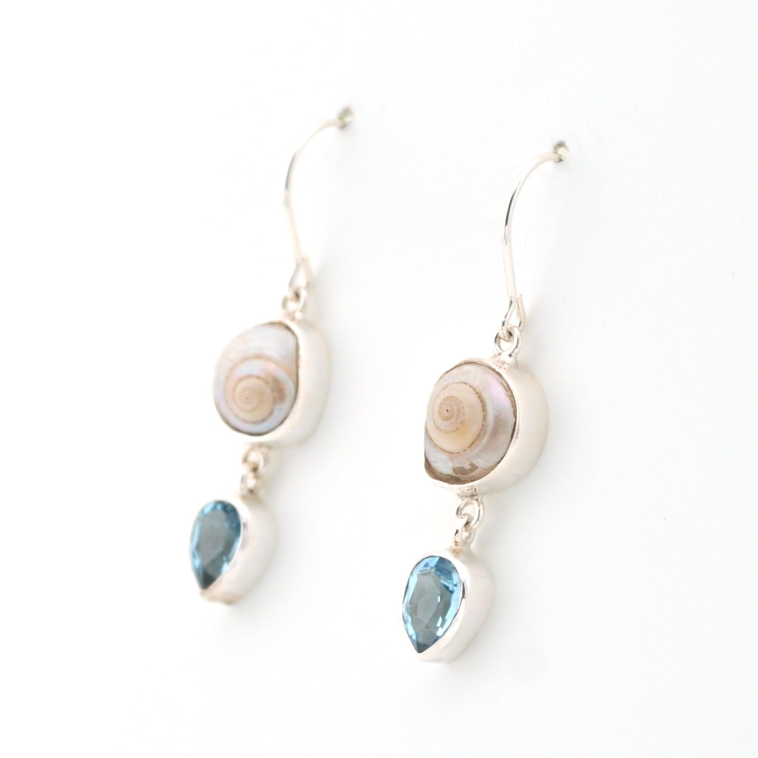 Pair of earrings with shell and blue gemstone drops on a white background