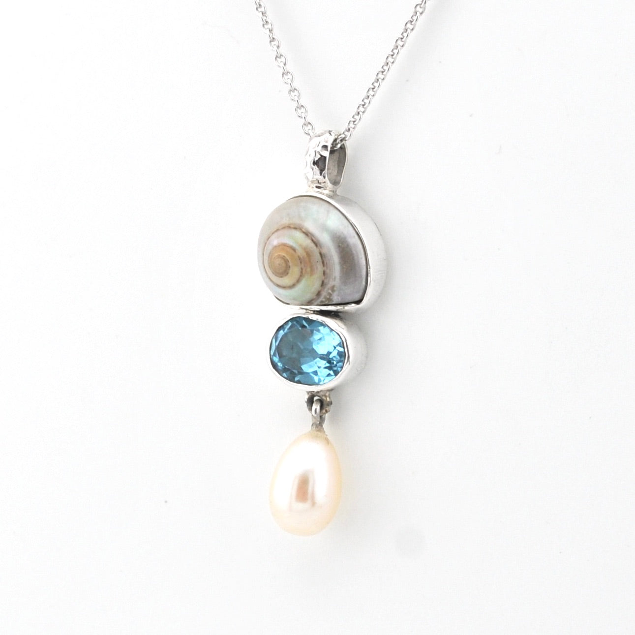 Silver pendant with a pearl and blue gemstone on a white background