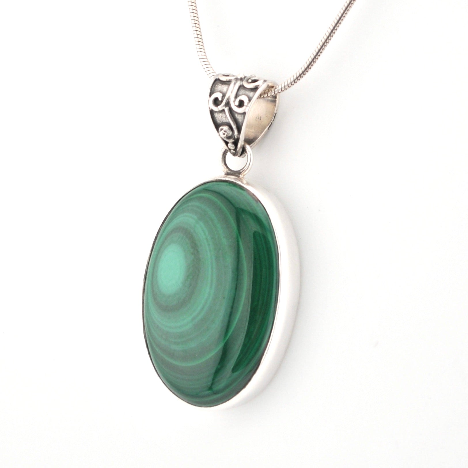 Green stone pendant on a silver chain against a white background