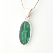Green malachite pendant on a silver chain against a white background