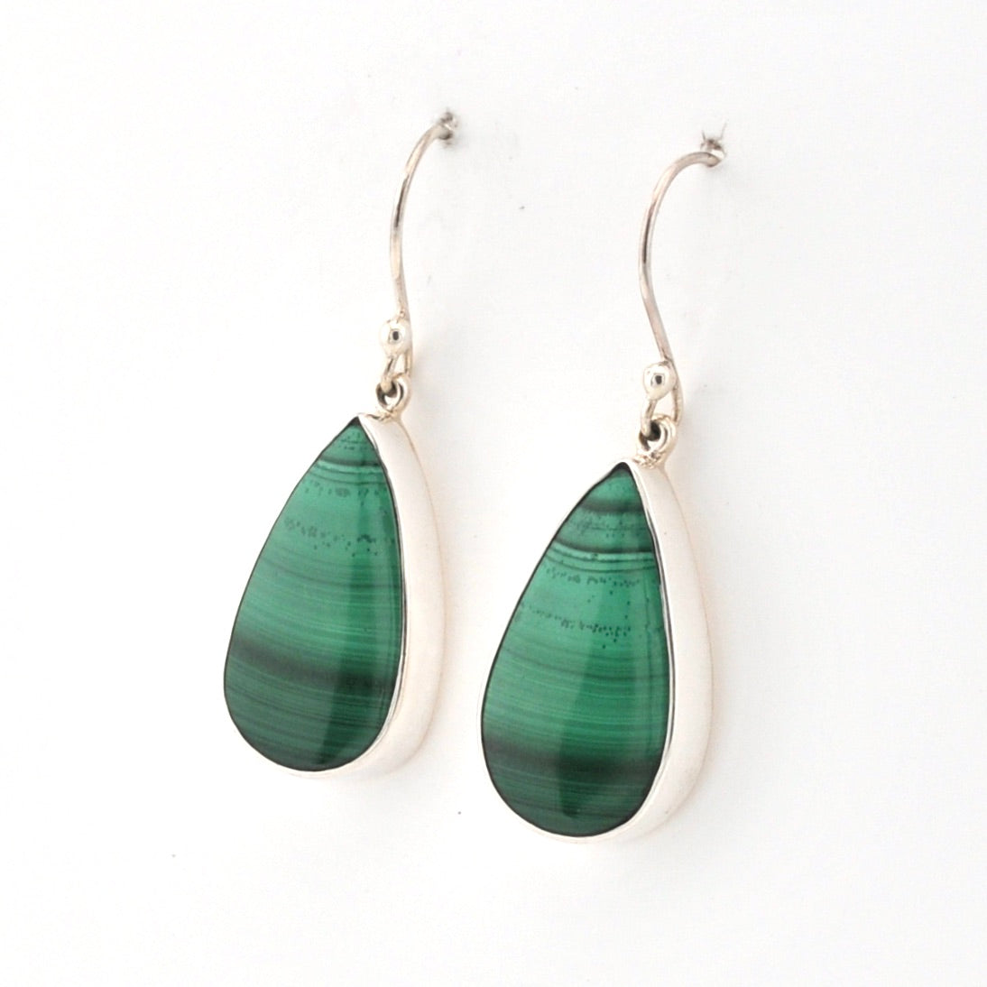 Teardrop-shaped green earrings with silver hooks on a white background