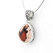 Silver pendant with a red stone on a white background