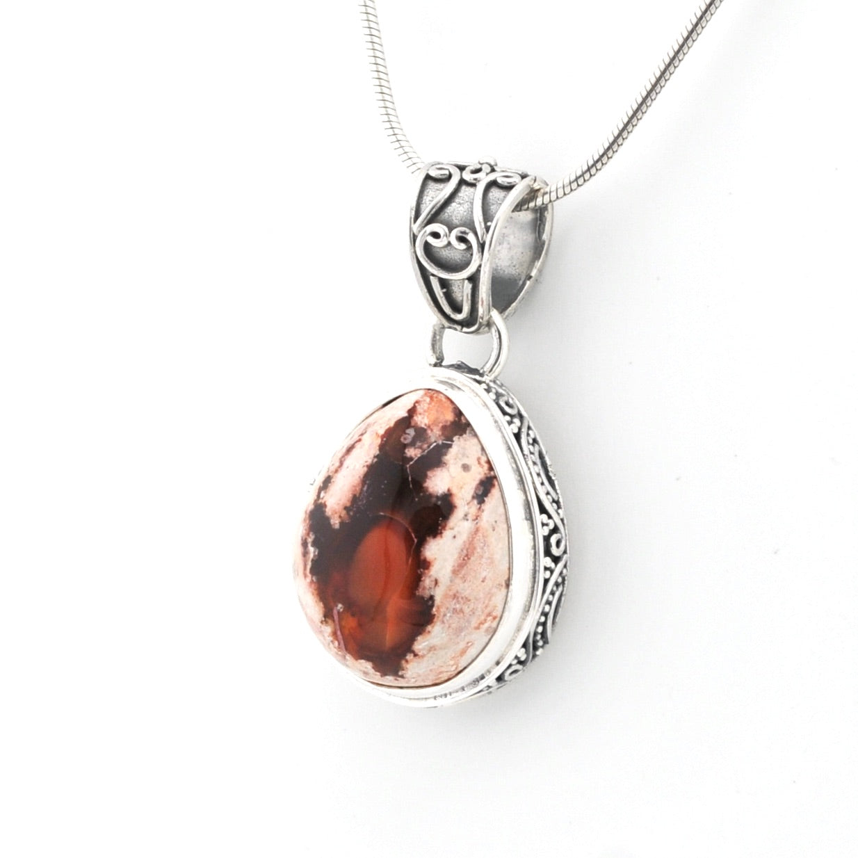 Silver pendant with a red stone on a white background