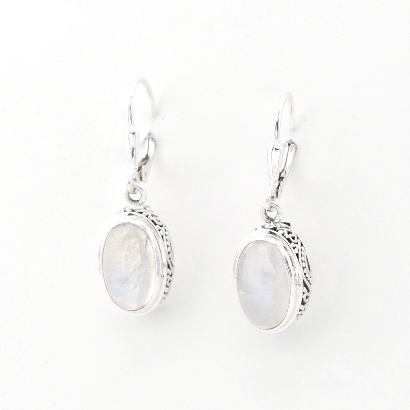 Pair of silver earrings with oval gemstones on a white background