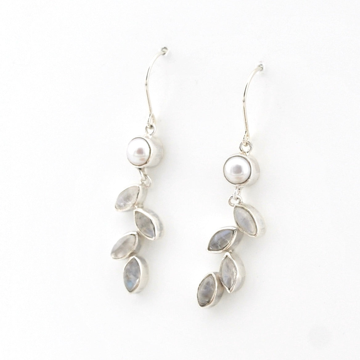 Silver earrings with pearls and leaf-shaped stones on a white background