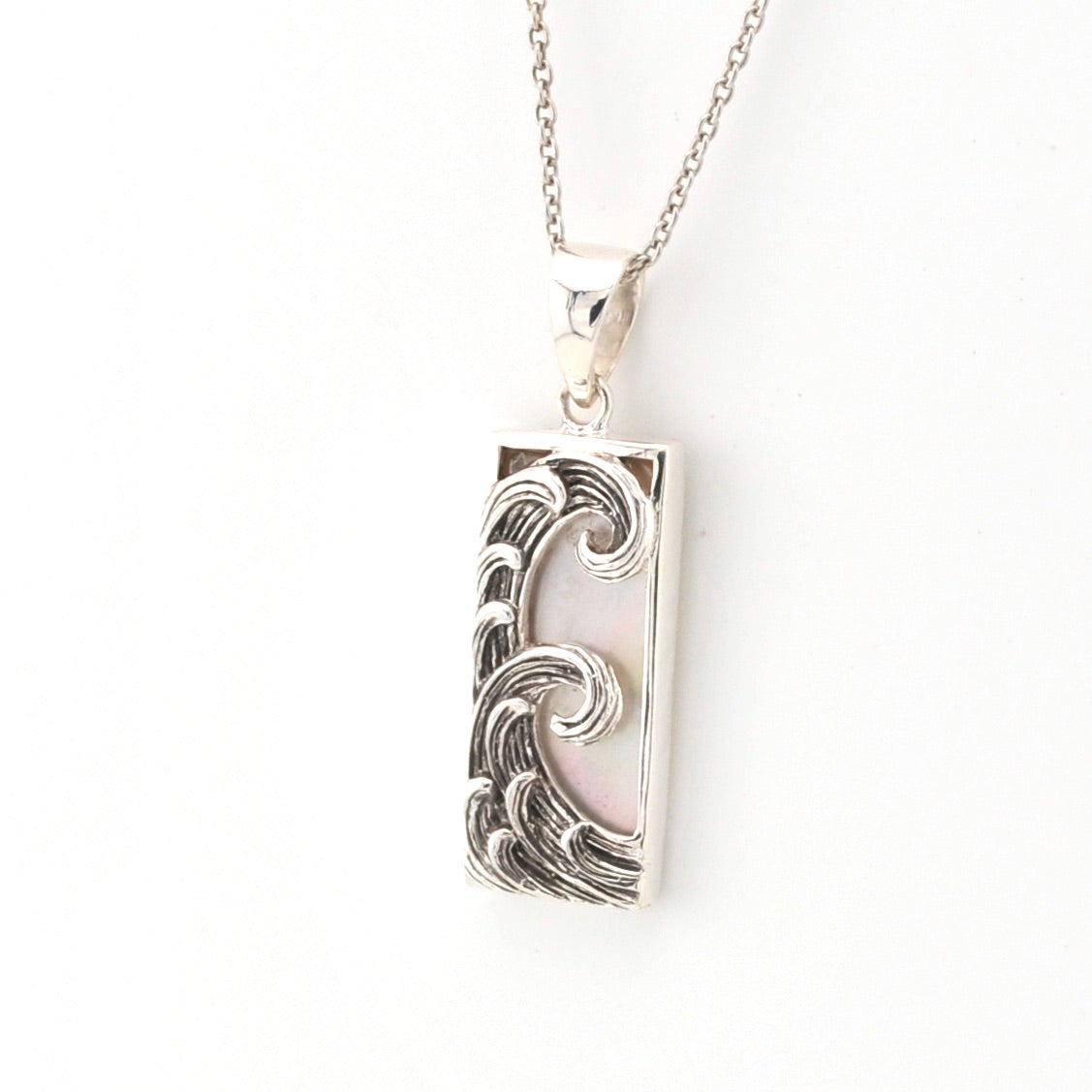 Silver pendant with wave design on a white background
