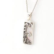 Silver pendant with wave design on a white background