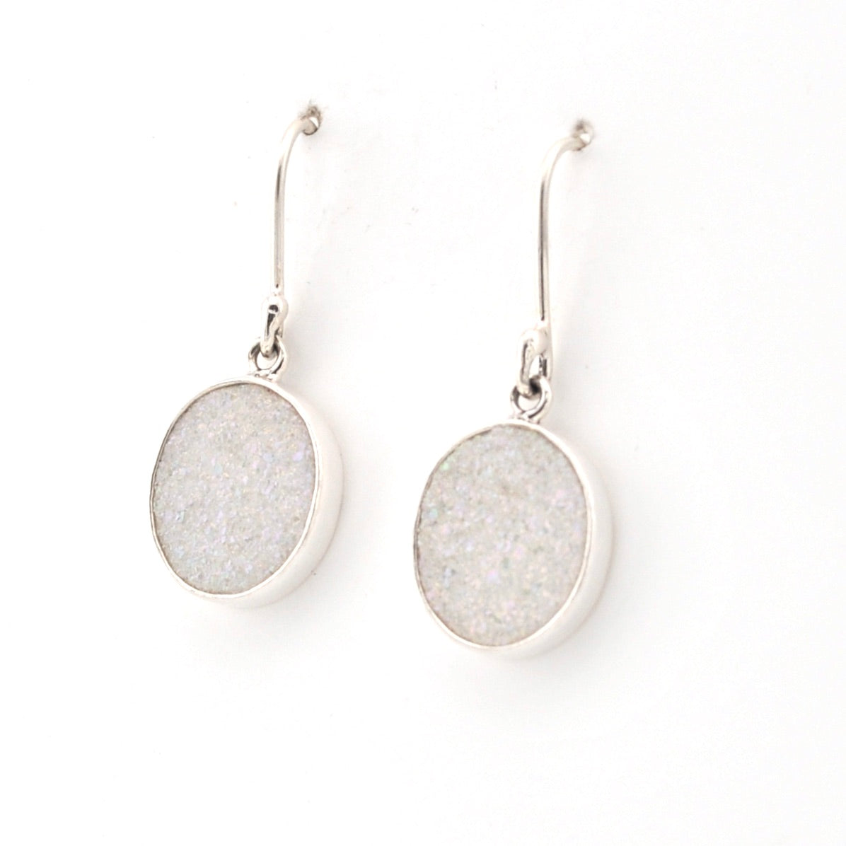 Pair of silver earrings with round, light gray stones on a white background