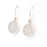 Pair of silver earrings with round, light gray stones on a white background