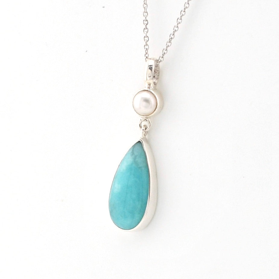 Necklace with a blue teardrop pendant and pearl on a white background