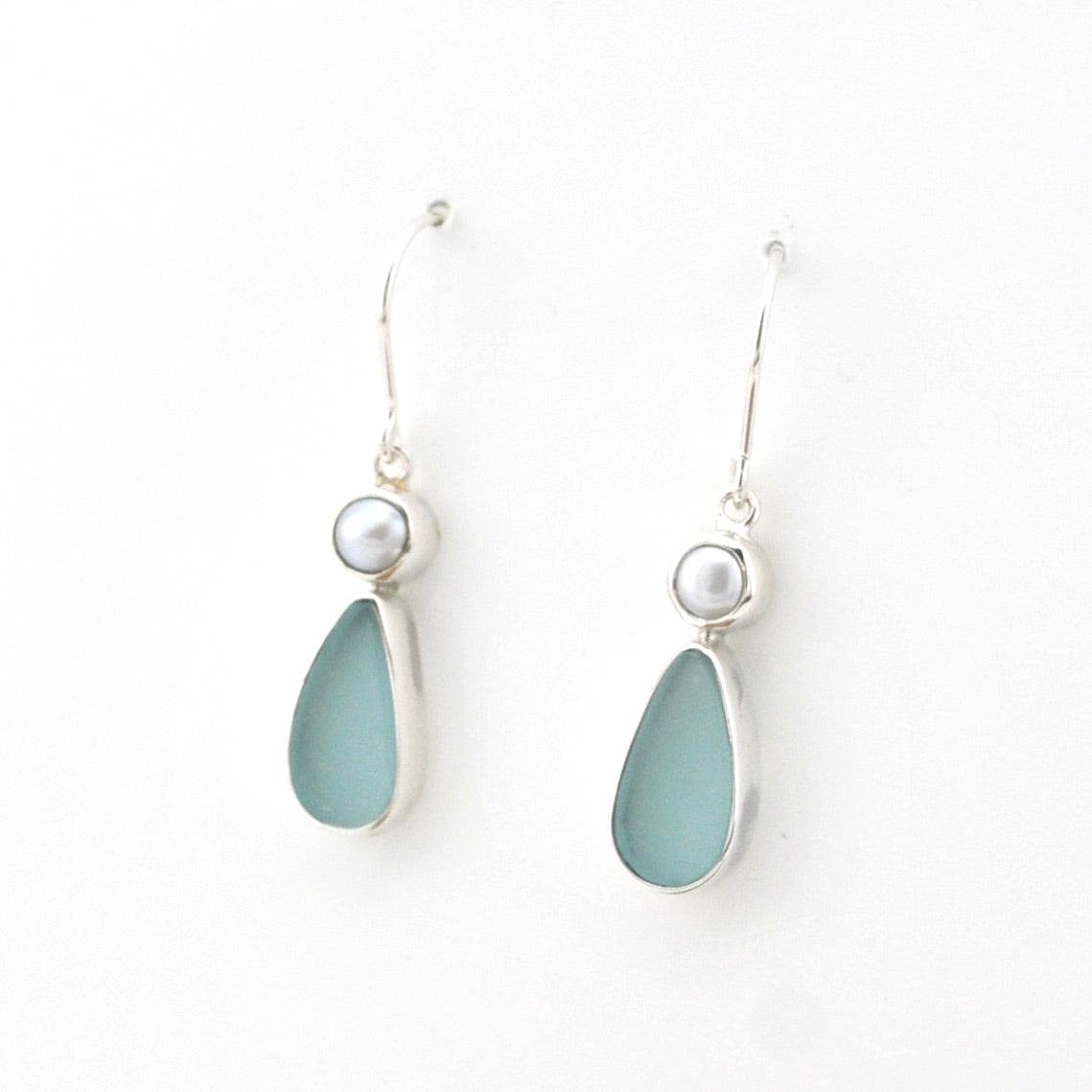 Pair of earrings with light blue teardrop-shaped stones and pearl-like tops on a white background