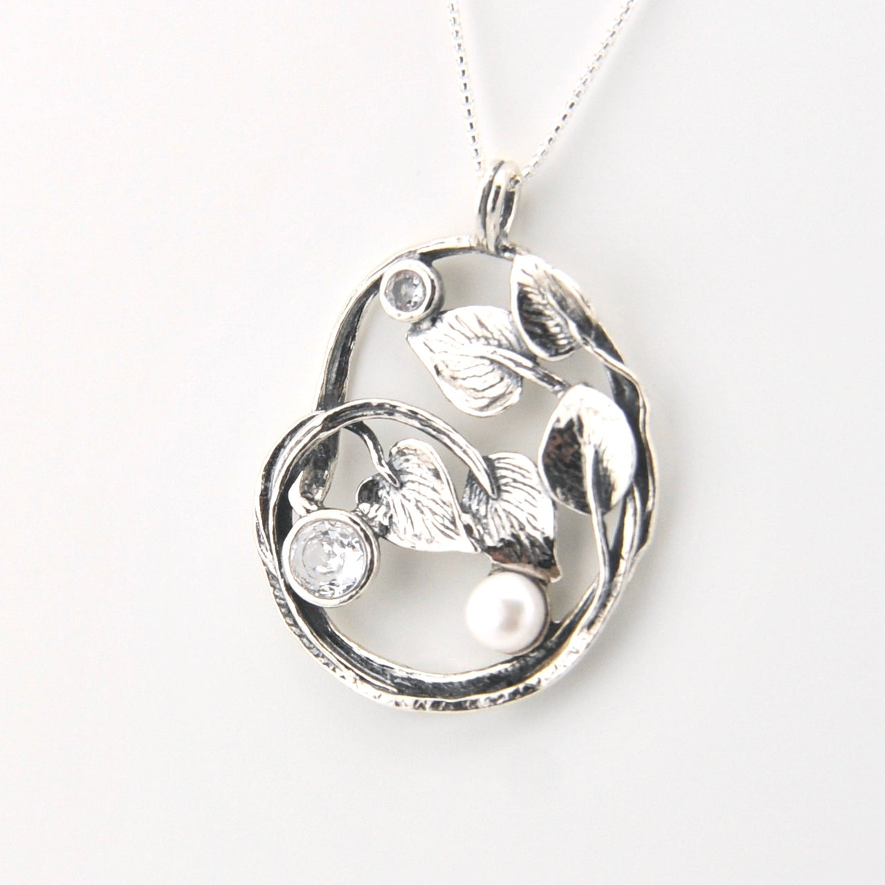 Silver pendant with floral design and pearls on a white background