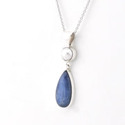 Necklace with a blue teardrop pendant and pearl on a white background