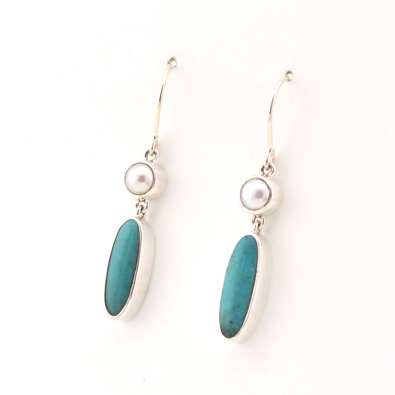 Pair of earrings with turquoise stones and pearl-like tops on a white background
