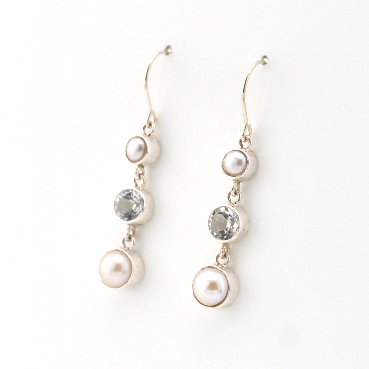 Pair of pearl and topaz drop earrings on a white background