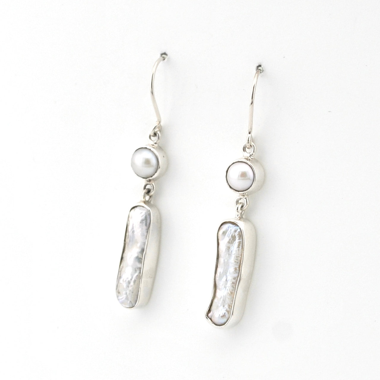 Pair of silver earrings with pearl drops on a white background