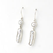 Pair of silver earrings with pearl drops on a white background