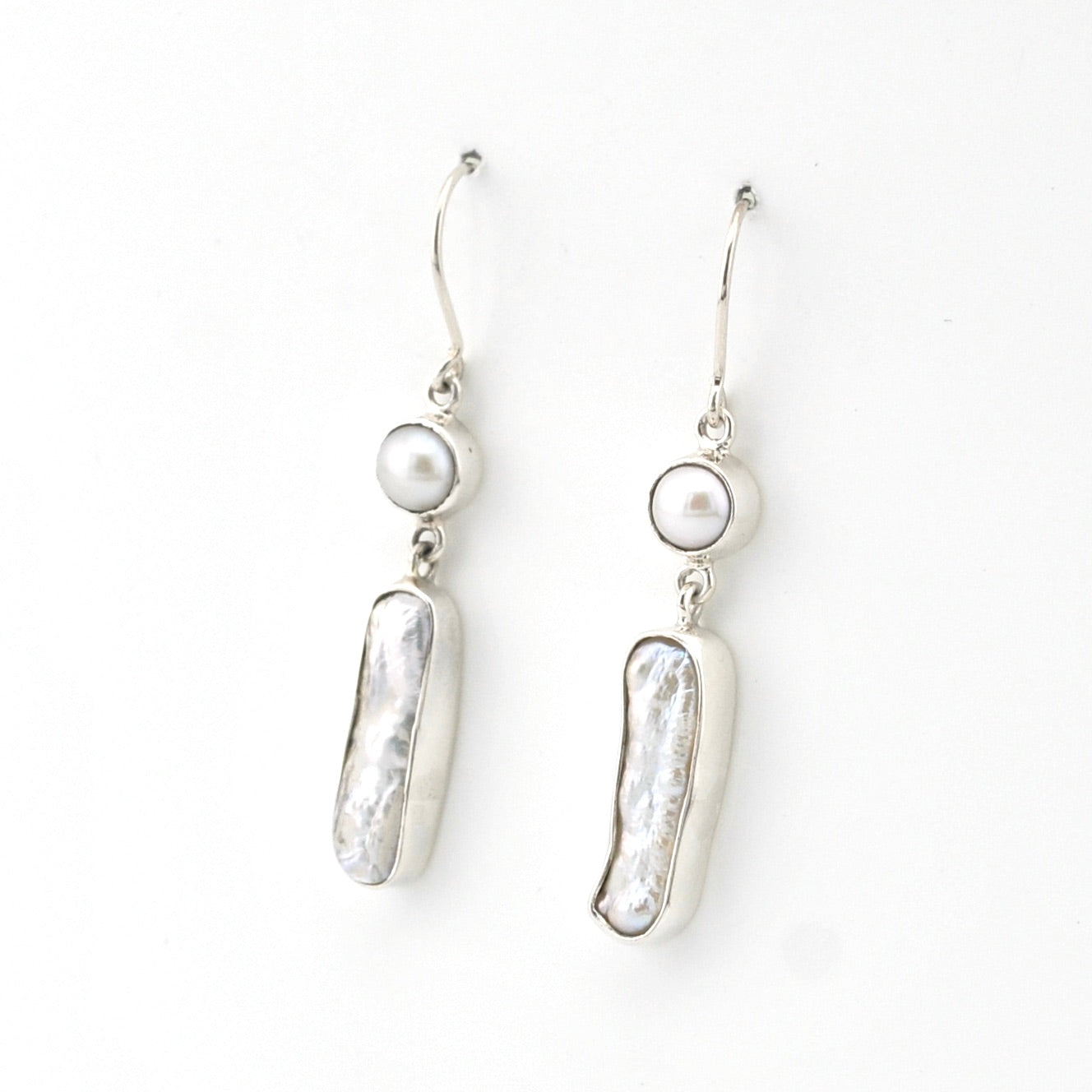 Pair of silver earrings with pearl drops on a white background