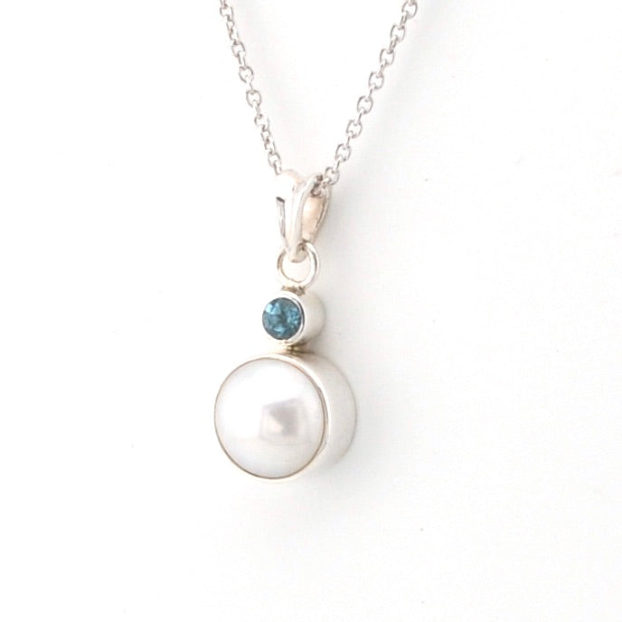 Pearl necklace with a blue gemstone on a white background