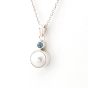 Pearl necklace with a blue gemstone on a white background