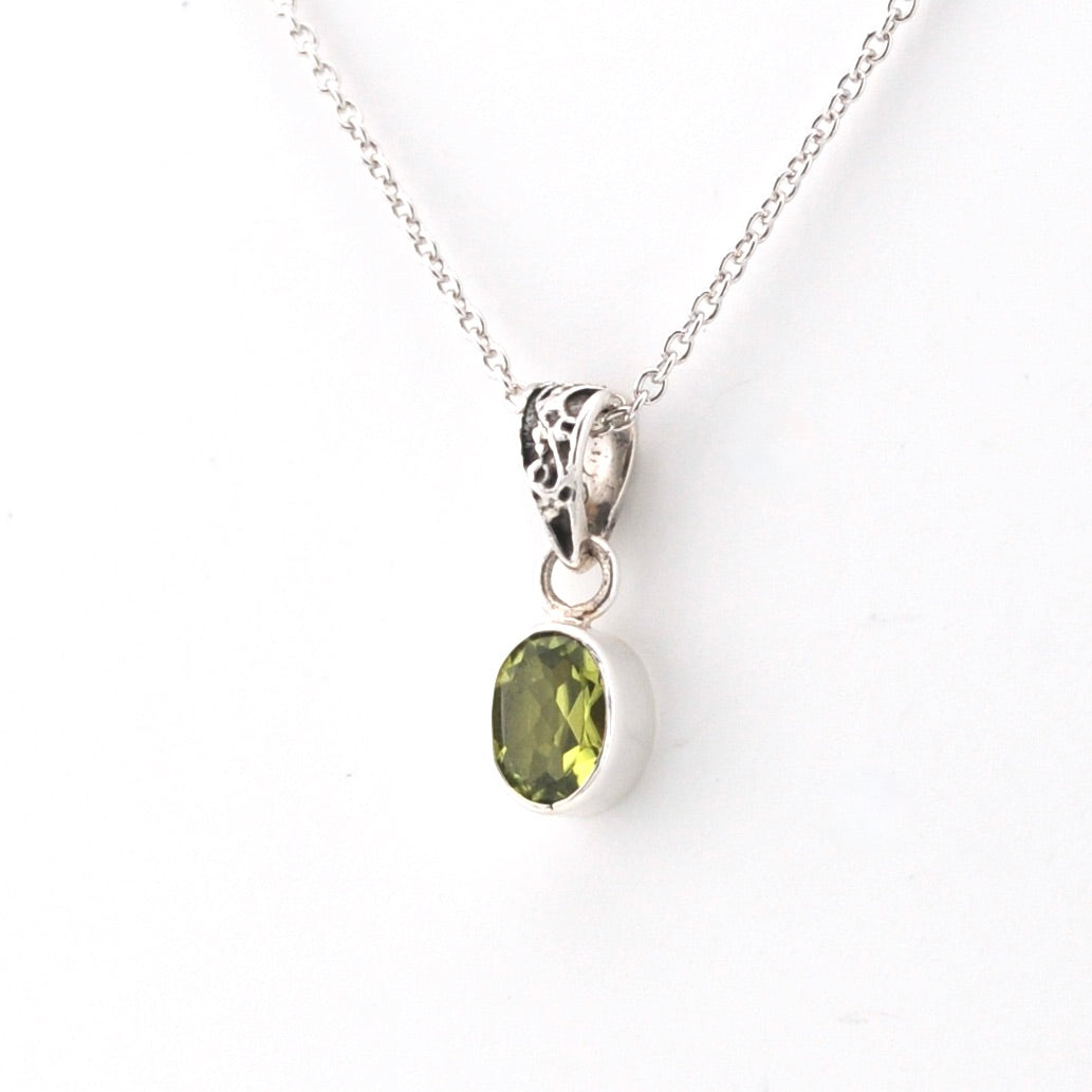 Silver pendant with a green gemstone on a white background