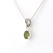 Silver pendant with a green gemstone on a white background
