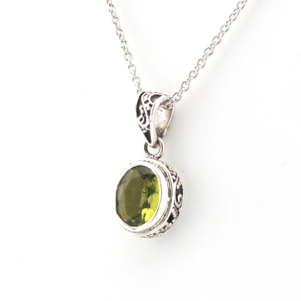 Silver pendant with a green gemstone on a white background