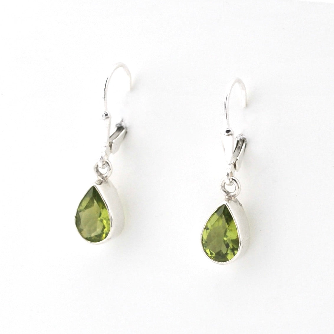 Silver earrings with peridot teardrop gems on white background.