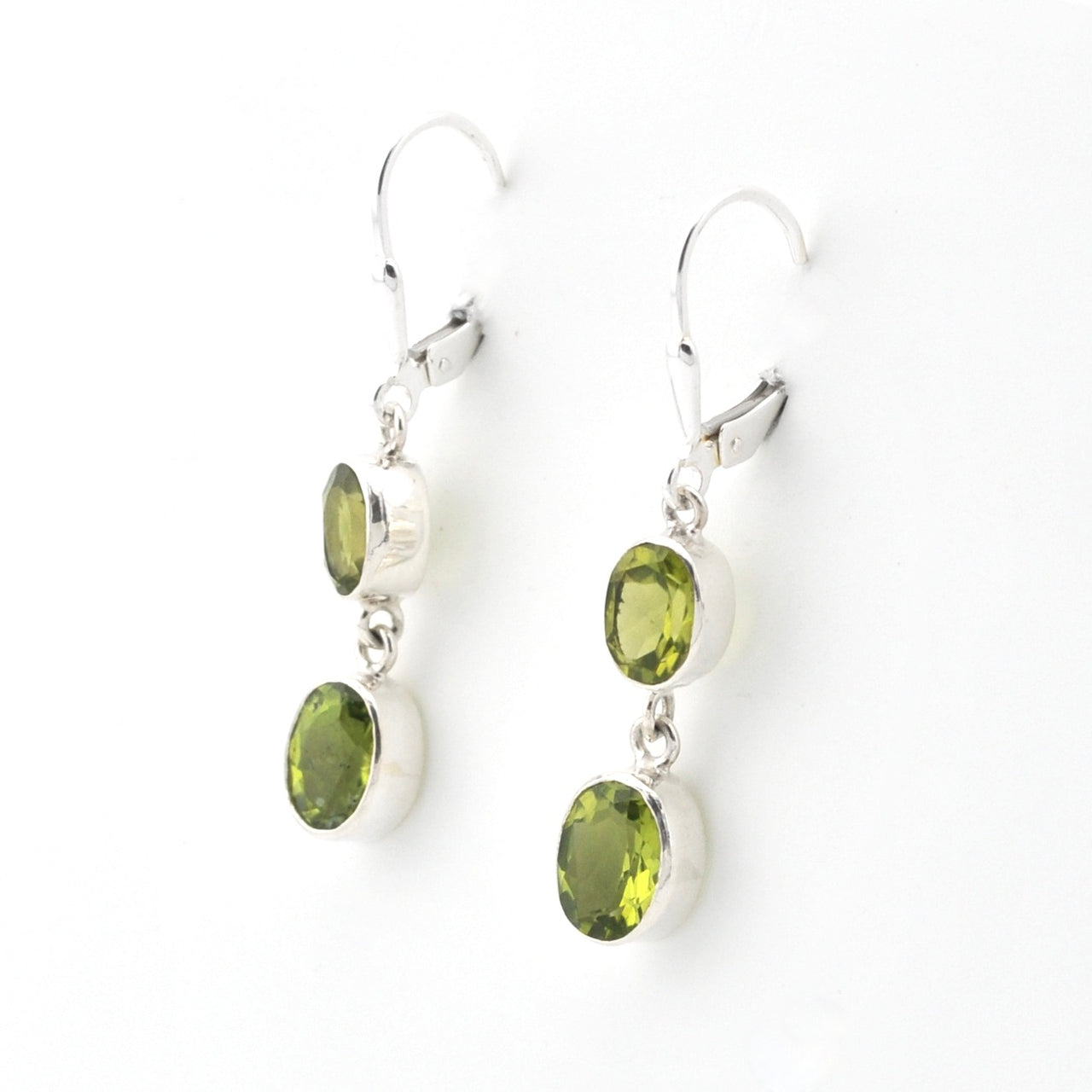 Silver earrings with green gemstones on a white background