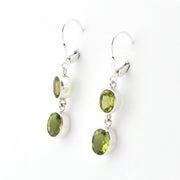 Silver earrings with green gemstones on a white background