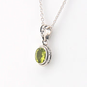 Silver pendant with a green gemstone on a white background