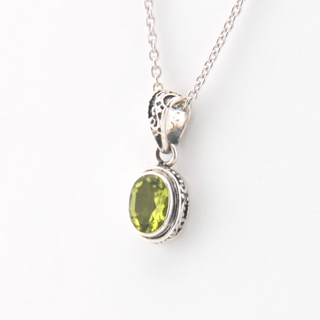 Silver pendant with a green gemstone on a white background
