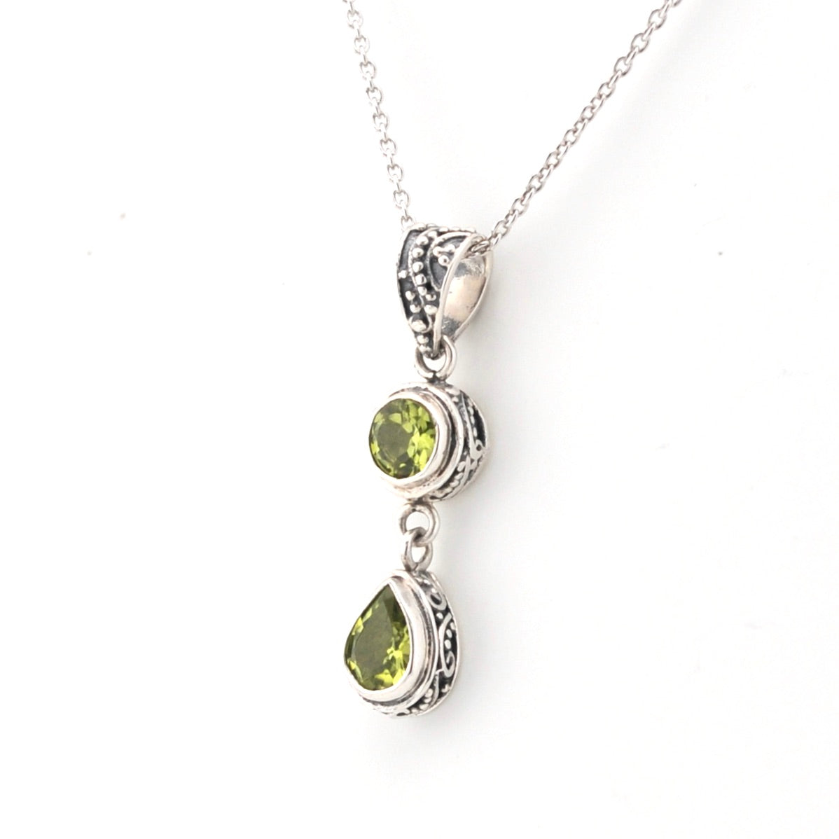 Silver necklace with green gemstone pendants on a white background