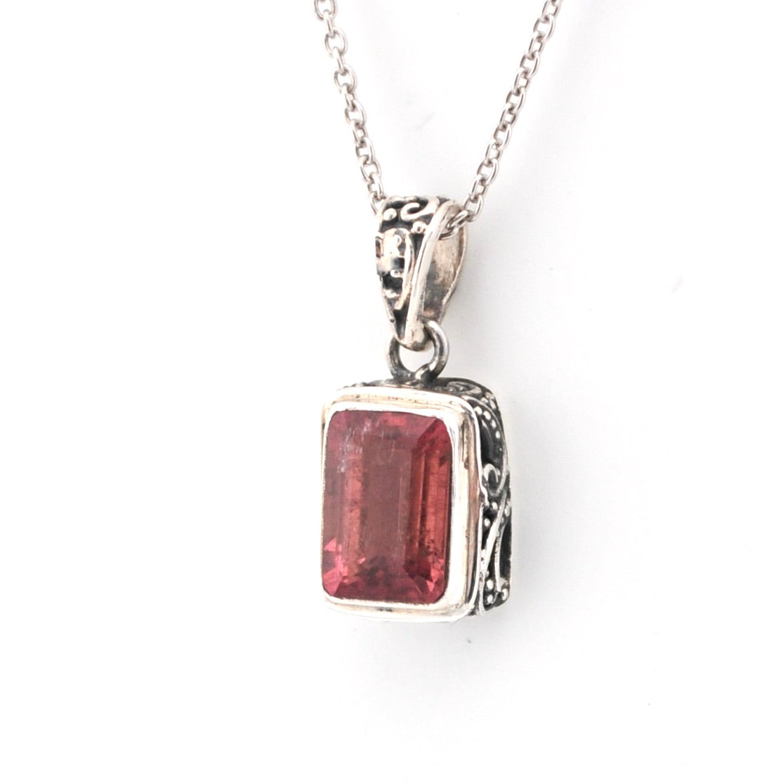Silver pendant with a red gemstone on a white background