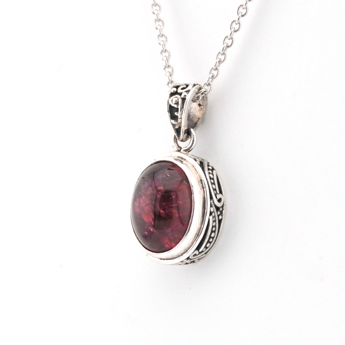 Silver pendant with a red gemstone on a white background