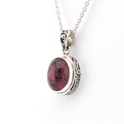 Silver pendant with a red gemstone on a white background