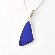 Blue sea glass pendant on a silver chain against a white background