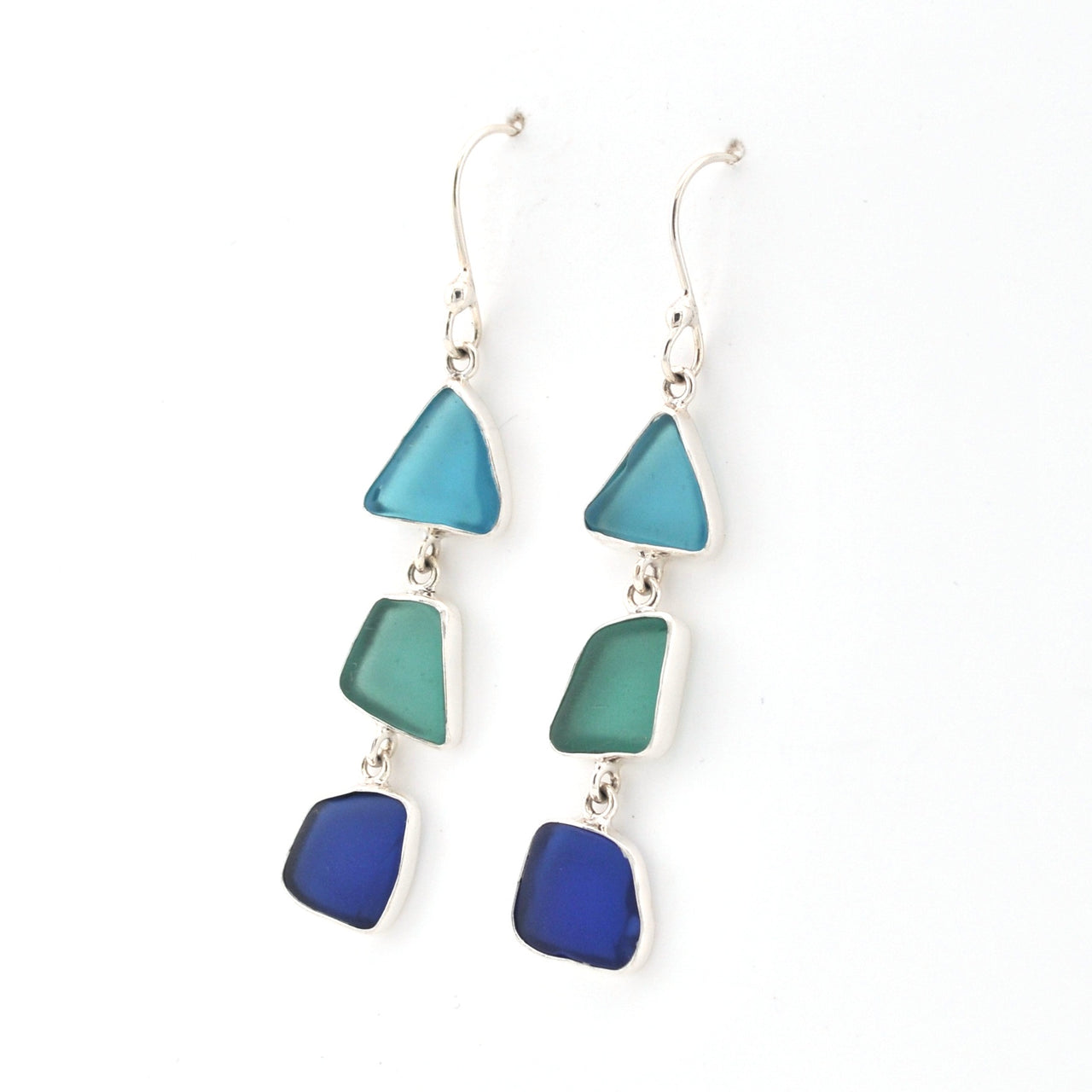 Pair of earrings with blue and green triangular glass on a white background