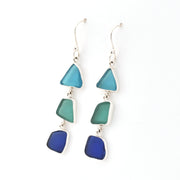 Pair of earrings with blue and green triangular glass on a white background
