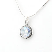 Silver necklace with a round pendant on a white background