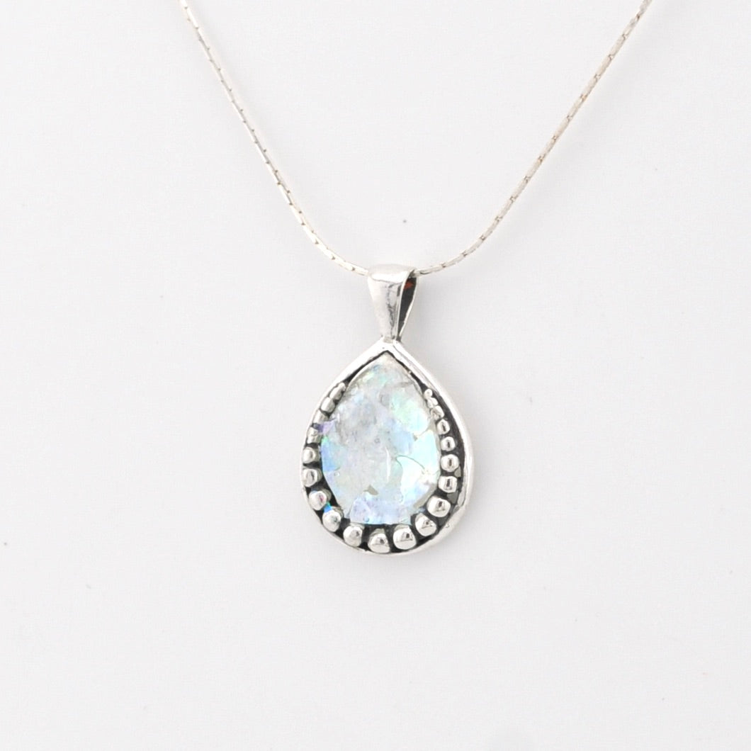Teardrop-shaped pendant with Roman glass on a white background