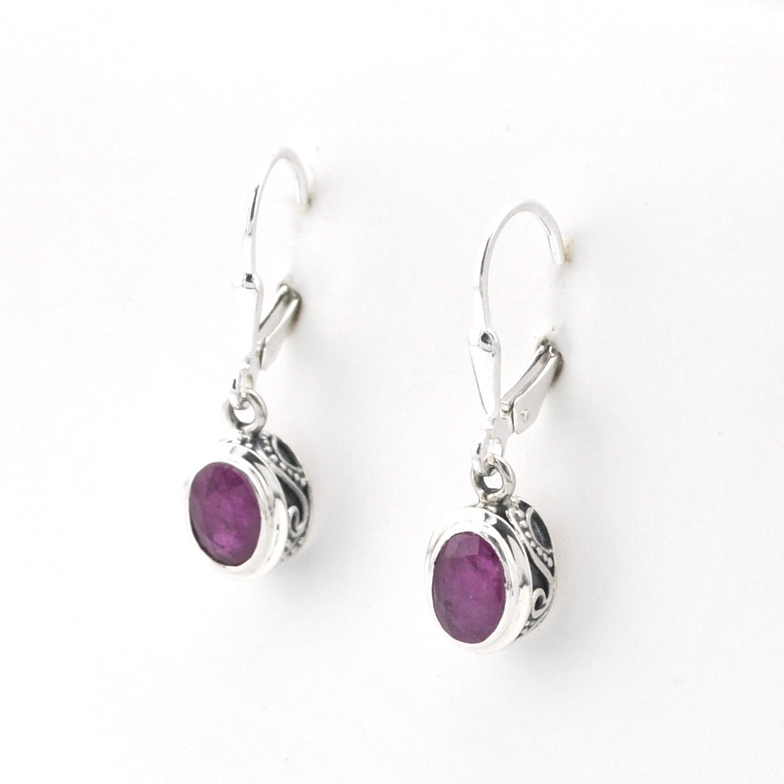 Silver earrings with purple gemstones on a white background