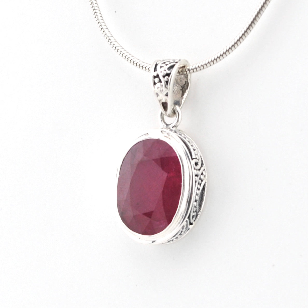 Silver pendant with a red gemstone on a white background