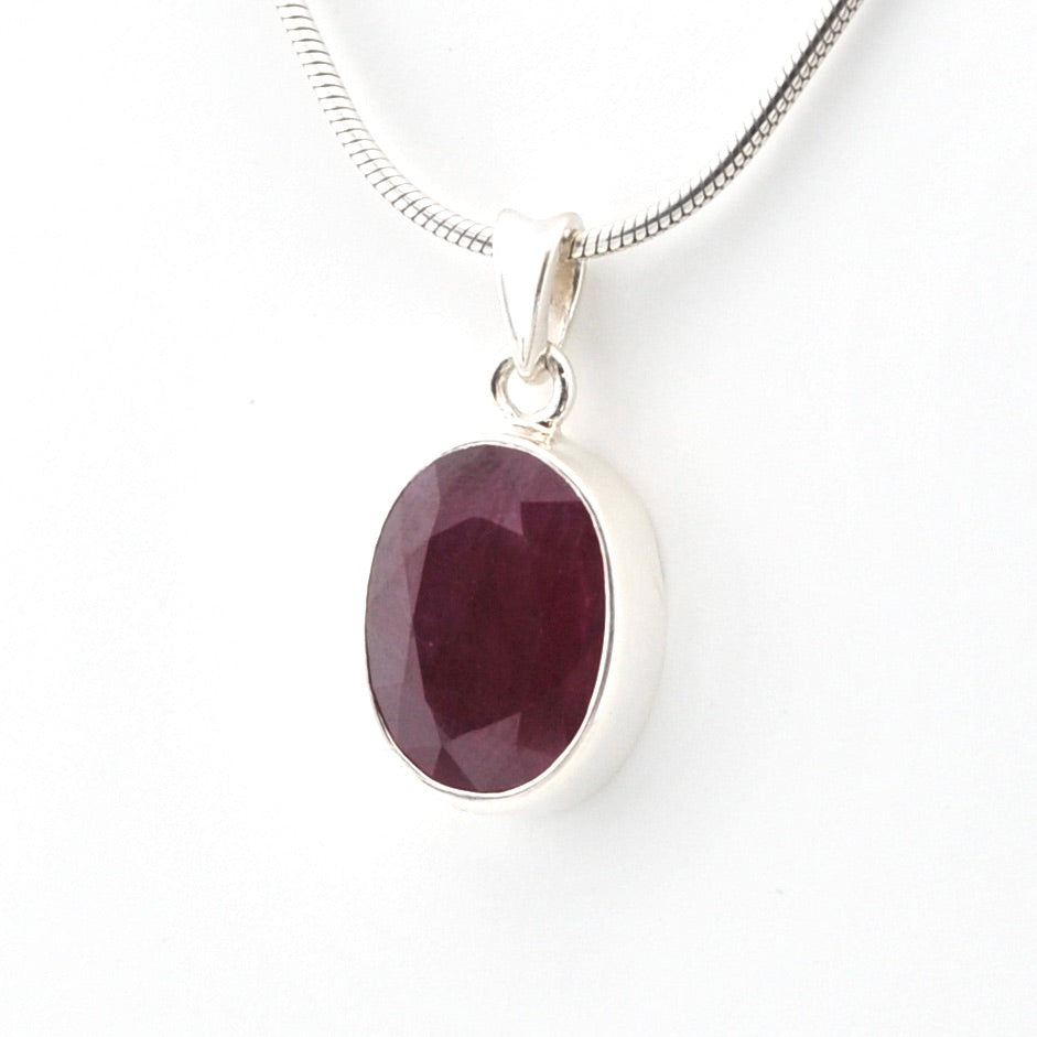 Silver pendant with a purple gemstone on a white background